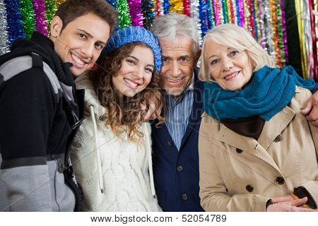 Portrait of happy family standing together against tinsels at store