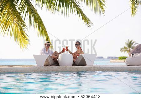 happy young couple relax and take fresh drink at summer vacation on swimmin pool