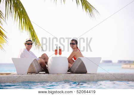 happy young couple relax and take fresh drink at summer vacation on swimmin pool