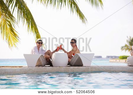 happy young couple relax and take fresh drink at summer vacation on swimmin pool