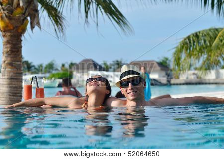 happy young couple relax and take fresh drink at summer vacation on swimmin pool