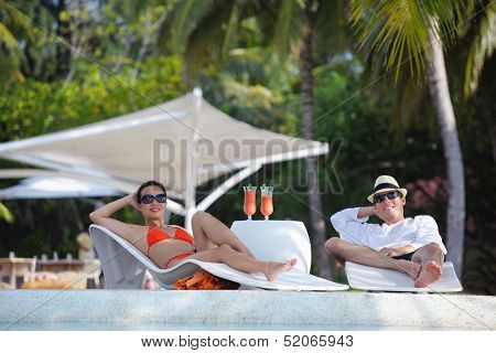 happy young couple relax and take fresh drink at summer vacation on swimmin pool