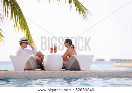 happy young couple relax and take fresh drink at summer vacation on swimmin pool