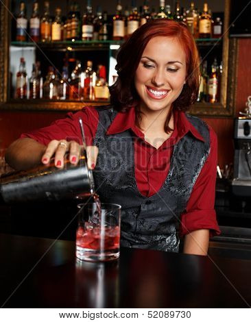 Beautiful redhead barmaid making cocktail