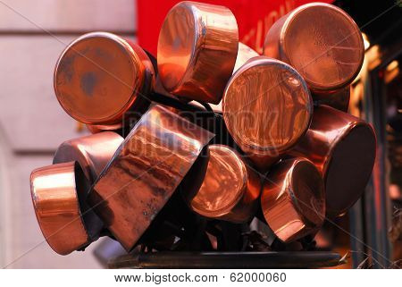 Bunch of old shiny copper pots near a restaurant