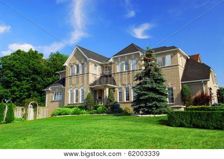 Large upscale residential home with bright green lawn and blue sky