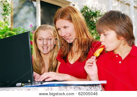 Mature woman working on computer at home with her children