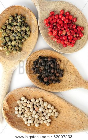 Four kinds of peppercorns in wooden cooking spoons