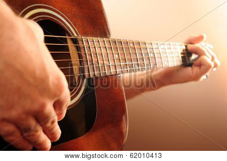 Hands of a person playing an acoustic guitar