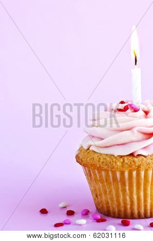 Single cupcake with icing sprinkles and candle
