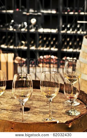 Row of wine glasses on barrel in winery cellar