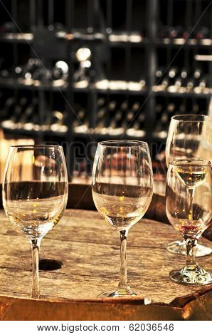 Row of wine glasses on barrel in winery cellar