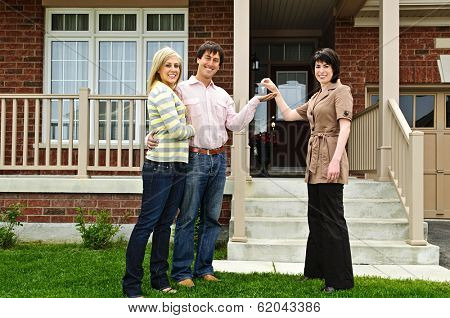 Happy couple getting keys to new house from real estate agent
