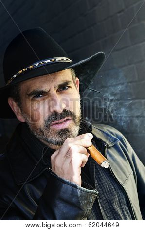 Man with beard in cowboy hat smoking cigar