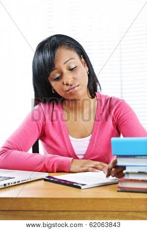Young black female student studying at desk looking sad