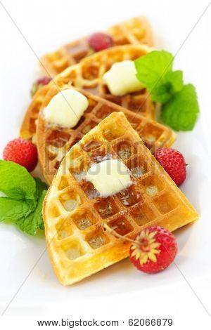 Plate of belgian waffles with fresh strawberries and pats of butter