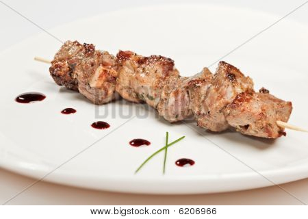 Brochette de porc sur la plaque blanche