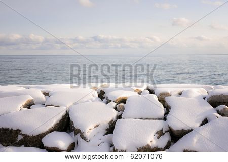 Rocks under snow on winter shore of lake Ontario in Sylvan park Toronto
