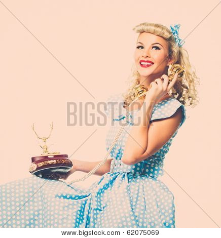 Coquette blond pin up style young woman in blue dress with vintage phone 