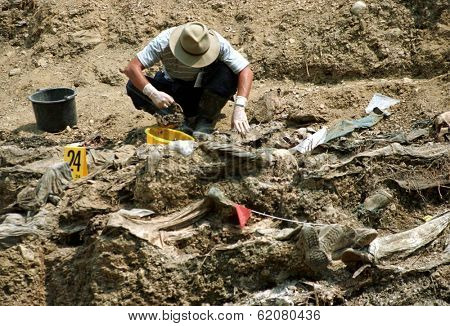 SREBRENICA, BOSNIA - JUNE 12: United Nations forensic experts unearth victims from a mass grave. The victims are among the estimated 8000 civilians killed by Bosnian Serb soldiers in July 1995 on June 12, 1996 in Srebencia, Bosnia.
