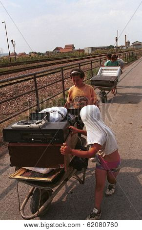 KOSOVO POLJE, KOSOVO, 29 JUNE 1999 --- A Kosovar Gypsy family flees their home after ethnic Albanians sought revenge on Gypsies who collaborated with Serbs during the war of independence.