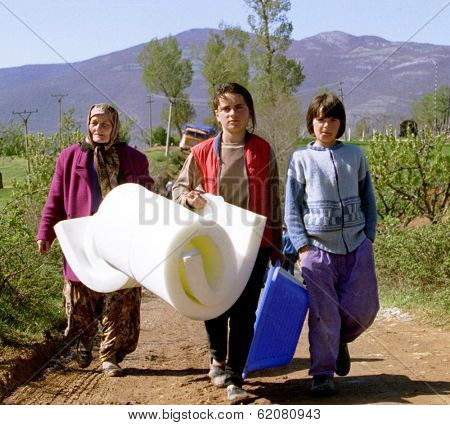 KUKES, ALBANIA - APRIL 17: A grandmother and her two granddaughters walk to their tent at a refugee camp along the Kosovo border after receiving a mattress from an international relief agency  on April 17, 1999 in Kukes, Albania