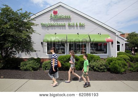 WOODBURY COMMON - JULY 9: Pedestrians walk past an Applebee's restaurant in Woodbury Common, New York, on Tuesday, July 9, 2013. 