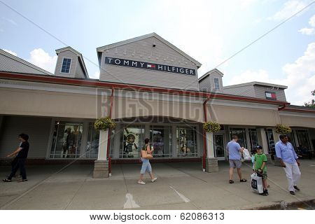 WOODBURY COMMON - JULY 9: Shoppers walk past a Tommy Hilfiger clothing outlet store in Woodbury Common, New York, on Tuesday, July 9, 2013. 