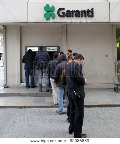 ISTANBUL, TURKEY - SATURDAY, MARCH 8, 2014: Customers wait on line to access money from an ATM machine at a Garanti Bank in Istanbul, Turkey, on Saturday, March 8, 2014. 