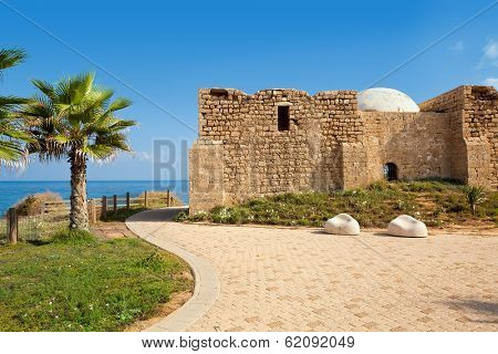 Promenade along Mediterranean sea coast with palms and ancient tomb of unknown shah in Ashkelon, Israel.