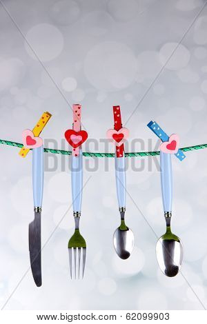 Cutlery dried on rope on bright background