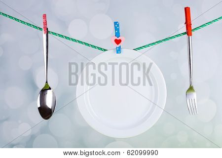 Tableware dried on rope on bright background
