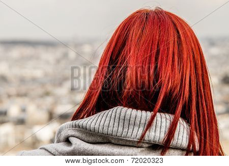 Girl with flaming red hair looking out over Paris