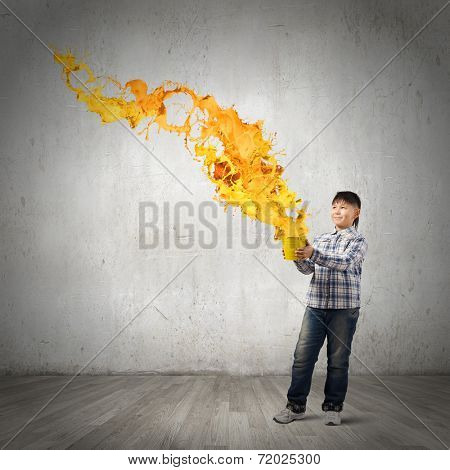 Young boy splashing colorful paint from bucket