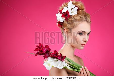 Beautiful girl, isolated on a pink background with varicoloured flowers in hairs, emotions, cosmetics