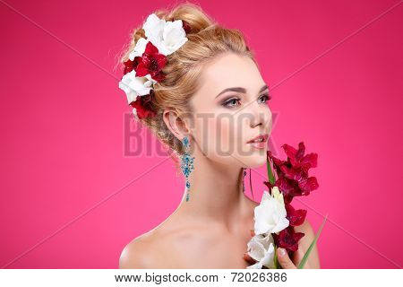 Beautiful girl, isolated on a pink background with varicoloured flowers in hairs, emotions, cosmetics