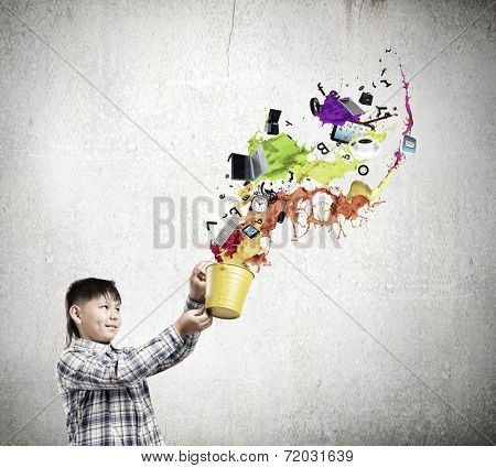 Young boy splashing colorful paint from bucket