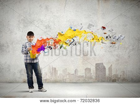 Young boy splashing colorful paint from bucket