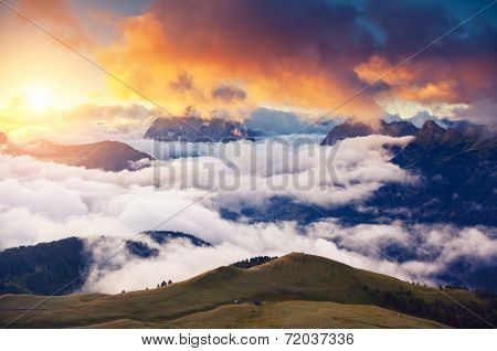 Great view of the foggy Val di Fassa valley with passo Sella. National Park. Dolomites, South Tyrol. Location Canazei, Campitello, Mazzin. Italy, Europe. Dramatic scene. Beauty world.