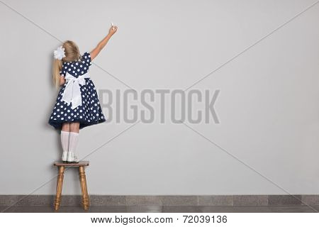 Little girl wrote in chalk on a gray wall. Girl is six years old.