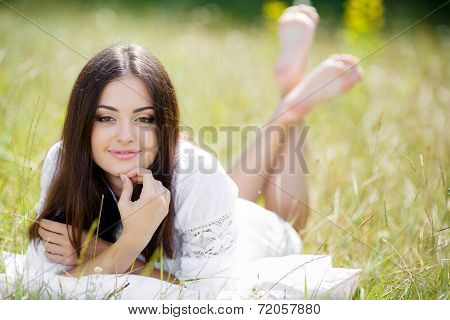 Girl resting on the soft pillow in fresh spring grass.