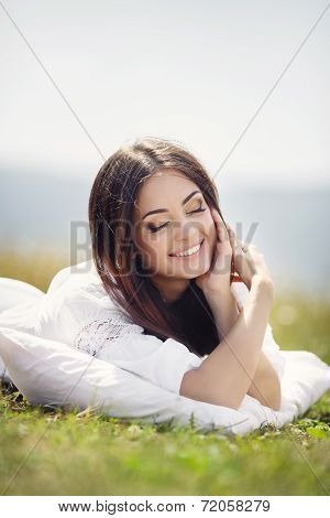 Young woman sleeping on soft pillow in fresh spring grass