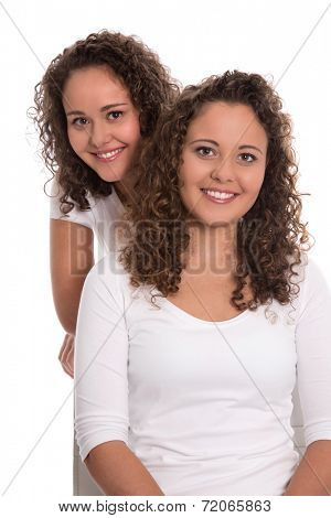 Real twin sisters: Portrait of two smiling isolated young woman with natural curls.