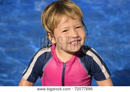 Happy kid with sun protection swimwear smiling in the swimming pool