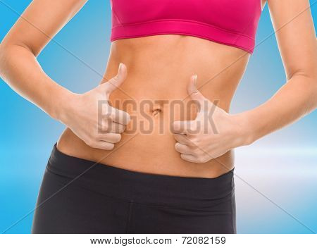 fitness and diet concept - close up of female abs and hands showing thumbs up