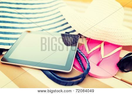 beach, summer, vacation, accessories and technology concept - close up of tablet pc computer and summer accessories on beach
