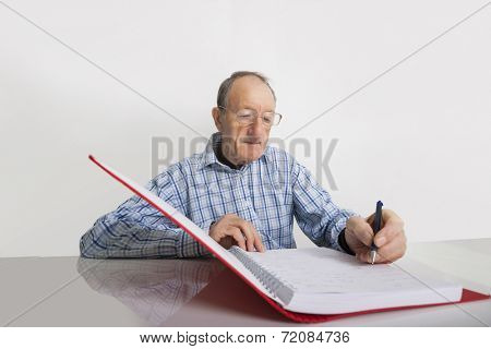 Senior businessman writing in file at desk