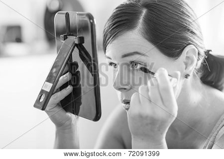 young wonderful woman applying her beautiful makeup in a mirror