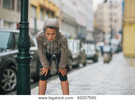 Woman Runner In The Rain Taking A Break And Stretching