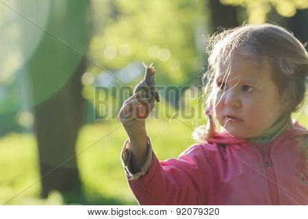 Curious Two Years Old Preschooler Girl With Short Pigtails Is Holding Edible Snail